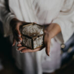 Boîte en verre avec fleurs blanches et bagues, date gravée. Photographe lifestyle mariage, élopement, shooting romantique.
