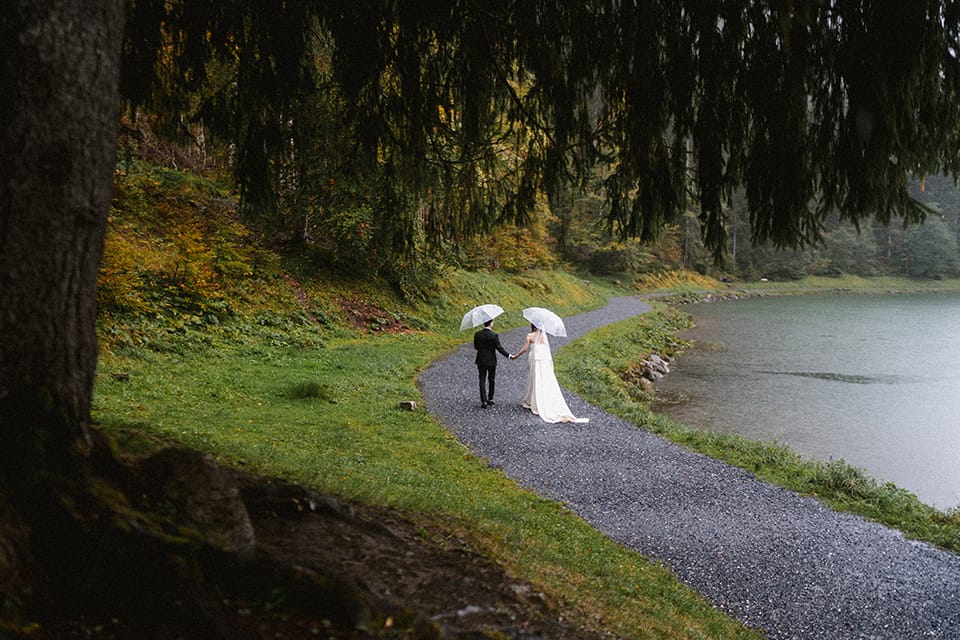 Couple marié sous parapluies, séance photo d'elopement au bord du lac, photographie lifestyle romantique en nature.