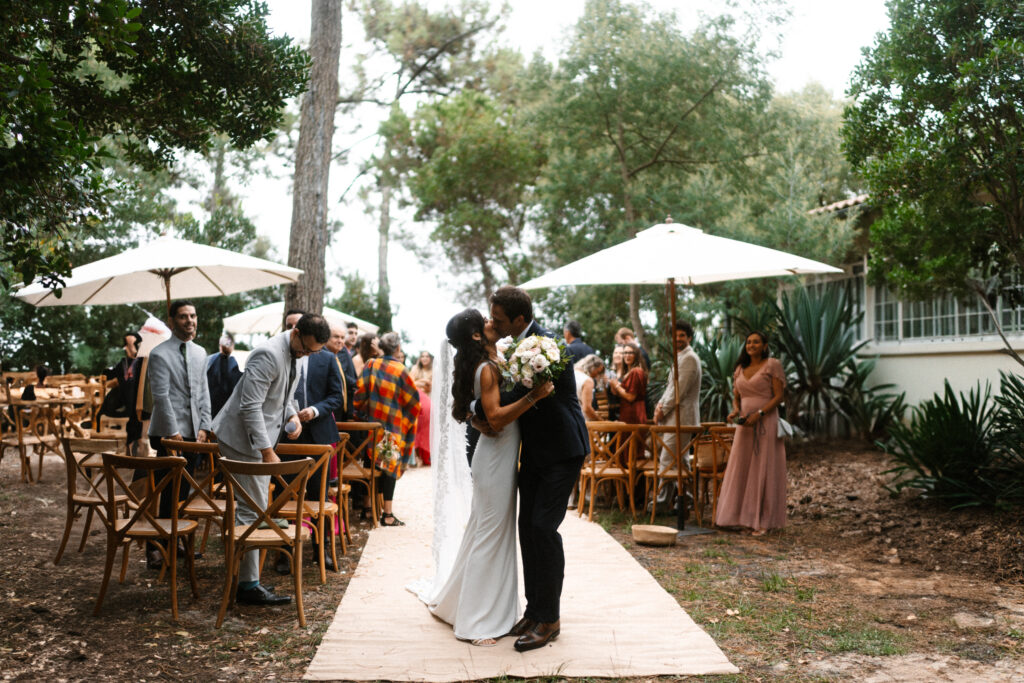 Mariage romantique en plein air, couple heureux s'embrassant, photographie lifestyle, événement intime, décor naturel.